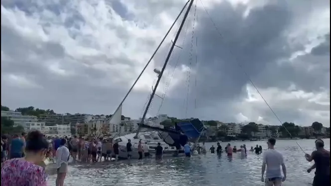 Nombroses persones ajuden a desencallar una embarcació a la platja de Santa Ponça